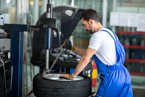Mechanik zdejmujący oponę z felgi za pomocą specjalnej maszyny